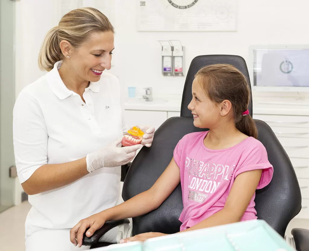 Dr. Paula Göser erklärt einem Mädchen eine Zahnspange in der kieferorthopädischen Praxis in Köln